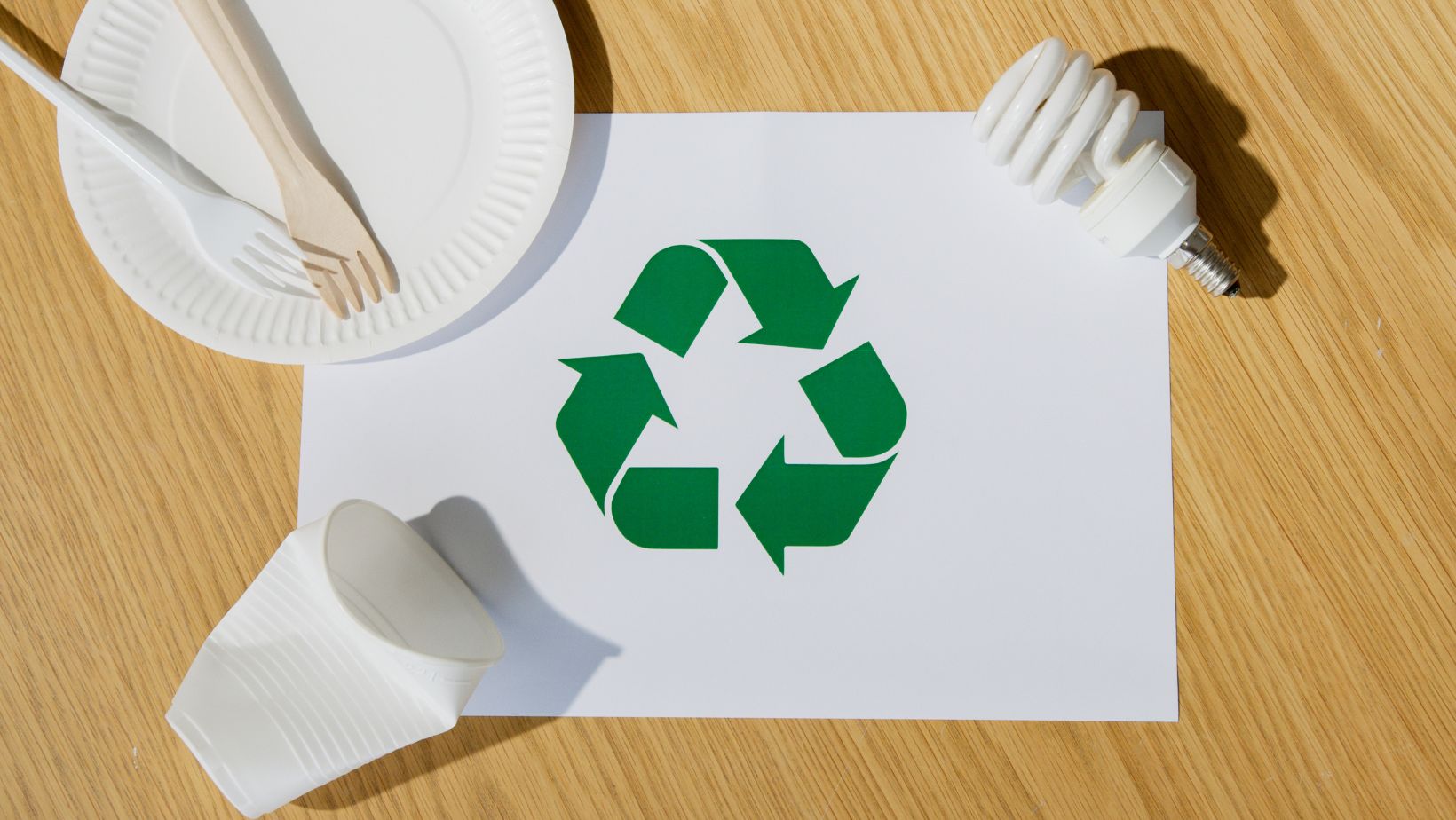 Recycling icon on a piece of paper with recyclable trash around it