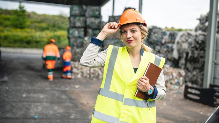 A worker holding onto their hard hat in a transfer station