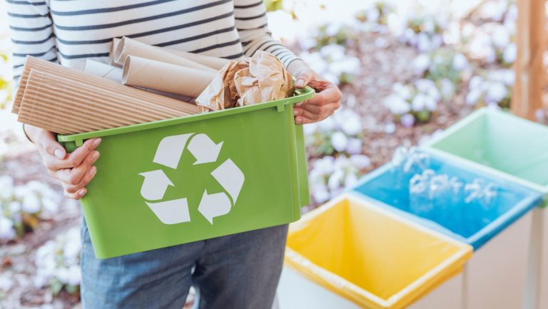 A person holding a recycling bin