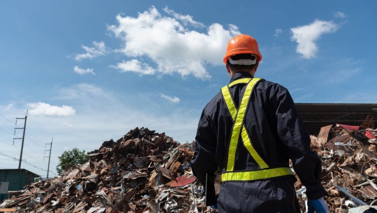 Piles of scrap metal at a metal recycling facility with a worker in front of it